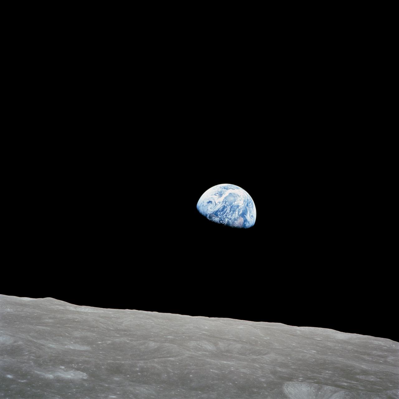'Earthrise': the half-lit Earth rising over the grey, cratered lunar horizon, photographed from Apollo 8.